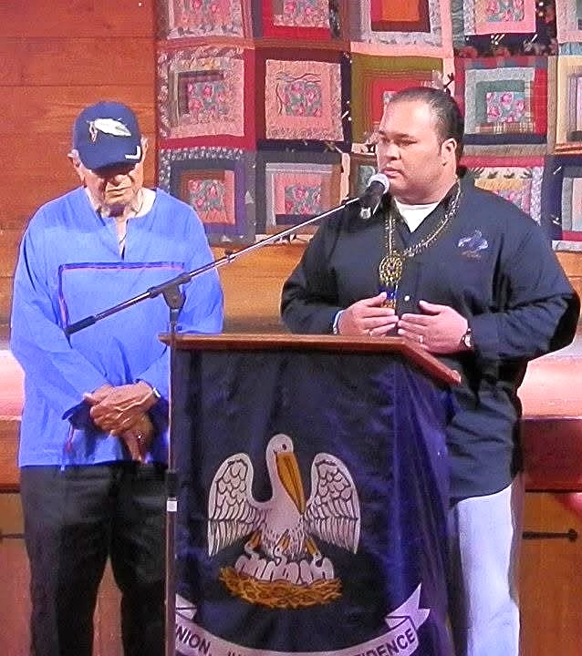 Chief speaking at podium beneath the Louisiana colors